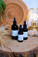 Drei schwarze Tropfflaschen mit Lion's Mane Flüssigextrakt auf einer Holzscheibe neben einer goldenen Drahtlampe.