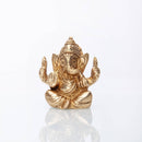 Goldene sitzende Ganesha-Statue mit detaillierten Verzierungen, Elefantenkopf, erhobenen Händen zum Segen und dekorativer Krone, auf weißem reflektierendem Hintergrund.