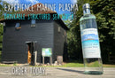 Eine Flasche Marine Plasma auf einem Holztisch, im Hintergrund ein schwarzes Gebäude, mit dem Text „EXPERIENCE MARINE PLASMA DRINKABLE STRUCTURED SEA WATER“ und „ORDER TODAY“.
