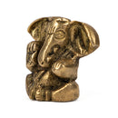 Kleine messingfarbene Figur des sitzenden Ganesha mit Elefantenkopf, erhobener segnender rechter Hand und Objekt in der linken, auf weißem Hintergrund.