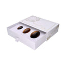 Geöffnete weiße Schachtel mit einem Set von drei polierten, braunen Tigerauge Yoni-Eiern in aufsteigenden Größen.