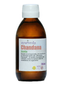  Eine braune Glasflasche mit weißem Schraubverschluss, beschriftet mit "Ayurveda autentico Chandana Aceite". Das Etikett beschreibt es als ayurvedisches Öl, basierend auf "Bhaisajya Ratnawali", angezeigt zur Wiederherstellung des Organismus, und zeigt "200 ml", "100% Natur" und ein Affen-Symbol.