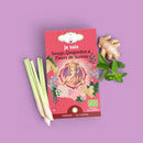 Eine rote Teepackung für ayurvedischen Salbei-, Ingwer- und Holunderblütentee mit einer Ganesha-Abbildung, umgeben von frischem Ingwer, Minze und Zitronengras.