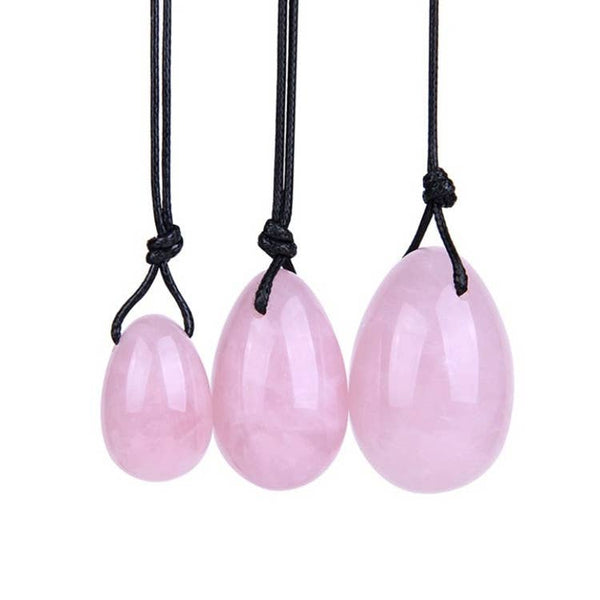 Set aus drei polierten, glatten, eiförmigen Rosenquarz-Anhängern in verschiedenen Größen (klein, mittel, groß), die jeweils an einer geknoteten schwarzen Kordel hängen.