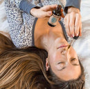 Eine liegende Frau benutzt eine Pipette, um PAAVANI Nasenöltropfen in ihre Nase zu träufeln.