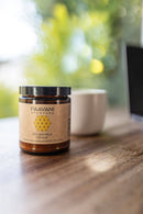 Glasgefäß mit Paavani Ayurveda Golden Milk (Haldi Doodh) Kurkuma-Nahrungsergänzungsmittel auf einem Holztisch nahe einem Fenster.