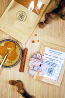 Eine Aufnahme von oben von der Mushroom Golden Latte Verpackung, einer Schale mit Pulver, Zimtstangen, Reishi-Pilzen und einem Kristall auf einer Holzoberfläche.