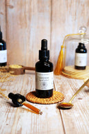 Eine einzelne Flasche Lion's Mane Flüssigextrakt steht auf einem gewebten Untersetzer mit einer Pipette und einem Löffel Flüssigkeit daneben.