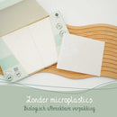 Offene Packung Spülmaschinentabs mit einem Tab auf einem Holzbrett. Niederländischer Text: "Zonder microplastics, Biologisch afbreekbare verpakking" (Ohne Mikroplastik, biologisch abbaubare Verpackung).