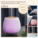 Eine Werbegrafik für den LINA-Aromadiffusor, ein rundes, weißes Lamellengerät mit Holzmaserungs-Oberseite, das rosa/lila leuchtet und Dampf abgibt, ist als „BEST SELLER“ gekennzeichnet. Eingeblendete Bilder zeigen das Hinzufügen von Öl, den rot leuchtenden Diffusor und dessen Basis.