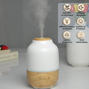 Aromatherapie-Diffusor aus Holz und weißer Keramik, der Dampf abgibt, mit sechs erklärenden Produkt-Symbolen.