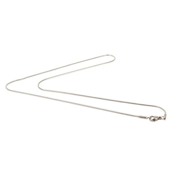 Dünne, polierte silberfarbene Schlangenkette, die in einer sanften Kurve liegt und den Verschluss an einem Ende zeigt.