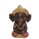 Eine dunkelbraune, meditierende Lord Ganesha Statue mit goldener Krone und Schmuck.