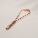 Ein einfacher, U-förmiger Zungenreiniger aus Kupfer mit strukturiertem Griff auf einem schlichten weißen Hintergrund.