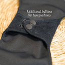 Nahaufnahme einer schwarzen wiederverwendbaren Binde mit zwei Reihen von Druckknöpfen zur Größenanpassung.