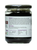 Braunes Chyawanprash in einem Glas mit schwarzem Deckel, auf dem ein Etikett mit Zutaten, Anwendung, Nährwertangaben und Firmenadresse zu sehen ist.