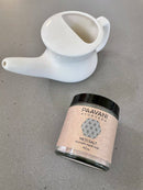 Flat Lay einer weißen Nasenspülkanne (Neti Pot) und eines Glases PAAVANI AYURVEDA Neti Salz auf einer grauen Theke.