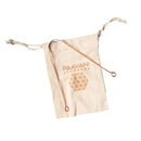 Zungenreiniger aus Kupfer, der auf einem Stoffbeutel mit der Aufschrift PAAVANI AYURVEDA liegt.