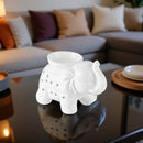 Weiße Elefanten-Duftlampe auf einem glänzenden Couchtisch vor einem Sofa im Wohnzimmer.