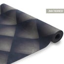 Nahaufnahme einer teilweise aufgerollten, 3 mm dicken Yogamatte mit einem dunklen, 3D-karierten oder rautenförmigen geometrischen Muster.