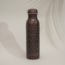 Kupfer-Wasserflasche mit Wabenstruktur und Schatten auf schlichtem Hintergrund