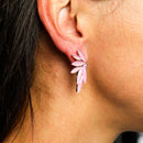 Nahaufnahme einer Frau, die einen auffälligen rosa-goldenen Ohrring trägt.