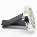 Eine Nahaufnahme des runden, silberfarbenen Auto-Lufterfrischers mit einem ausgeschnittenen, verzierten Lebensbaum-Motiv, befestigt an einem schwarzen Kunststoffclip für die Lüftungsdüse eines Fahrzeugs.