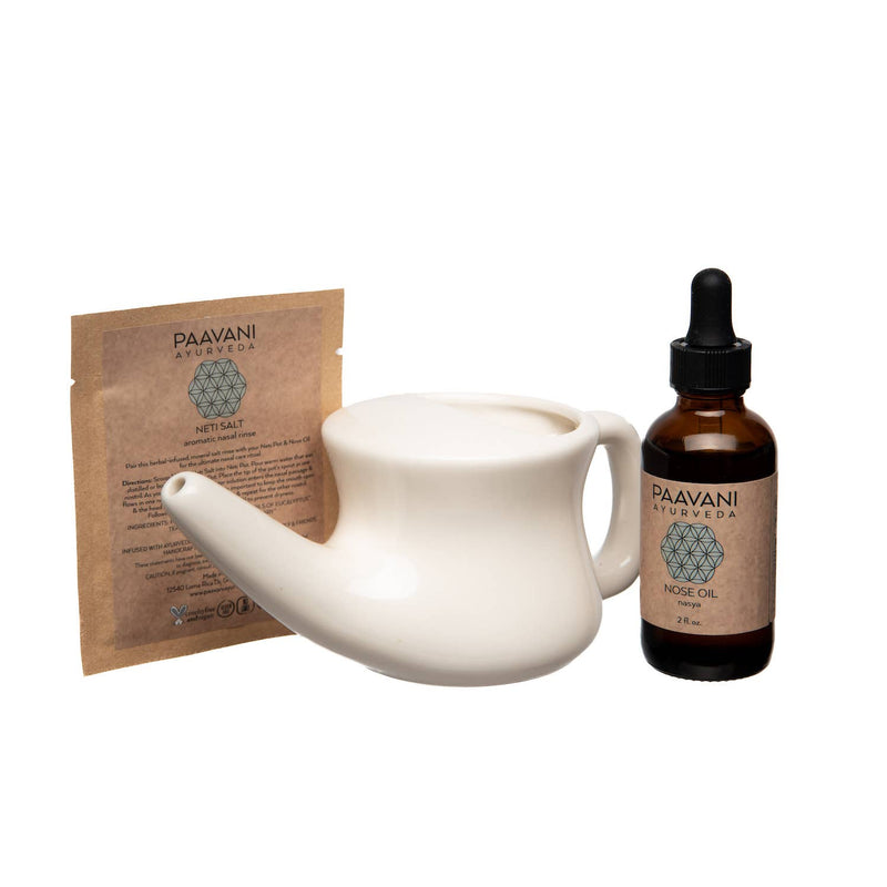  Ein weißer Neti-Topf, eine Packung "PAAVANI AYURVEDA NETI SALT aromatic nasal rinse" und eine Flasche "PAAVANI AYURVEDA NOSE OIL" auf einem weißen Hintergrund, die die Bestandteile des Nasenpflege-Ritual-Sets zeigen.