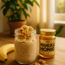 Ein Glas Manuka Honig MGO 250 neben Haferflocken mit Bananenscheiben und Walnüssen auf einem Holztisch.
