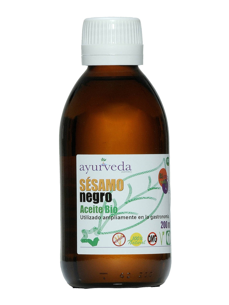 Eine braune Glasflasche mit einem weißen Deckel und einem weißen Etikett, auf dem groß "Ayurveda SÉSAMO negro Aceite Bio" steht, sowie "200 ml", "100% Natural" und "Sin Gluten" (glutenfrei) Logos.