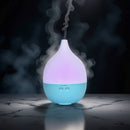 Ein elektrischer, tropfenförmiger Aroma-Diffusor mit blauem Boden und farbwechselnder Beleuchtung an der Oberseite, der in einer dunklen Umgebung Nebel ausstößt.