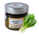 Ein Glas „Bärlauch Pesto“ mit silbernem Deckel und der Aufschrift „Ulrika’s Edition Gold“, daneben ein Bündel frischer, grüner Bärlauchblätter.
