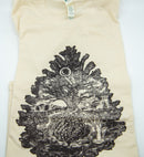 Ein gefaltetes, cremefarbenes T-Shirt mit einem detaillierten schwarzen Motiv eines Tannenzapfens, dessen Schuppen eine Miniaturlandschaft mit einem zentralen Baum umschließen.