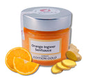 Jar of "Orange Ingwer Senfsauce" with silver lid, surrounded by sliced oranges and ginger. The bright orange sauce suggests a tangy, zesty flavor.
