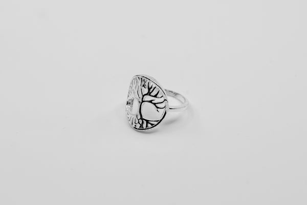Ein silberner Ring mit einem detaillierten ausgeschnittenen Lebensbaum-Motiv, auf einem weißen Hintergrund.