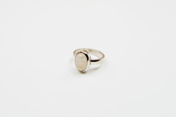 Ein silberner Ring mit glatter Ringschiene und einem großen, ovalen, irisierenden weißen Stein, auf einem weißen Hintergrund.