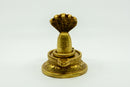 Eine goldene oder messingfarbene Shiva-Lingam-Statue mit einer detaillierten Haube einer zusammengerollten Kobra darüber, auf einem weißen Hintergrund.