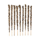 Ein Satz von zehn vertikalen, dicken Räucherstäbchen, die auf einem weißen Hintergrund stehen. Die Stäbchen sind dick mit einer Mischung aus natürlichem Pflanzenmaterial bedeckt, hauptsächlich hellvioletten und beigefarbenen Stücken, die wie getrocknete Lavendelblüten aussehen.