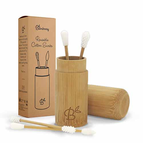 Ein Set von Bamboozy wiederverwendbaren Wattestäbchen in einem Bambushalter mit Deckel, zusammen mit der Kartonverpackung, zeigt die verschiedenen Spitzendesigns.