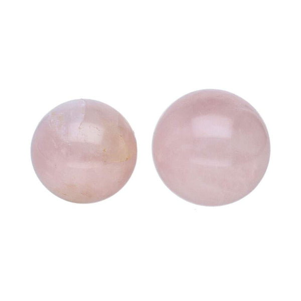 Paar glatter, polierter Kugeln (oder Perlen) aus hellrosa Rosenquarz, wobei eine etwas größer ist als die andere.