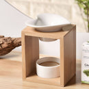 Eine Aromalampe aus Bambusholz mit einer herzförmigen Keramikschale, auf einer Oberfläche neben einer Schachtel Zedernholz-Ätherisches Öl.