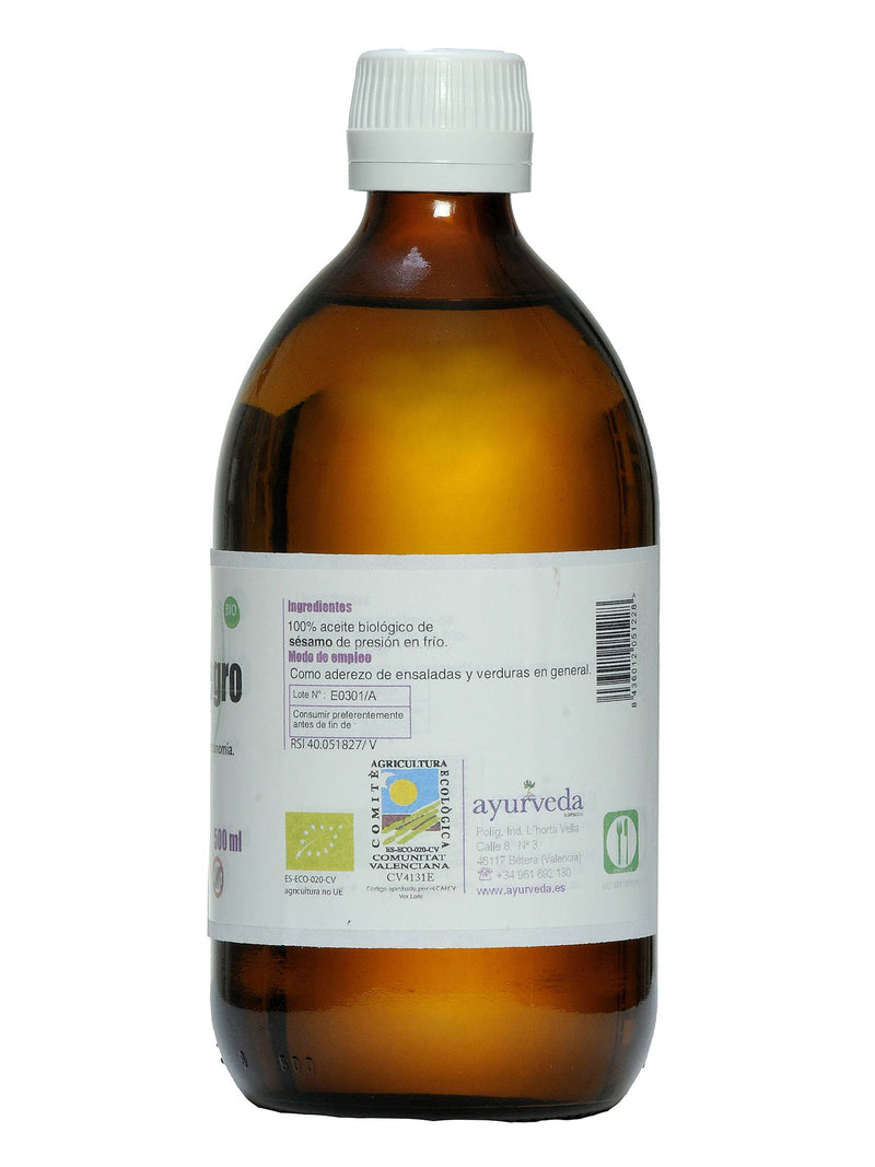Eine braune Glasflasche mit einem weißen Deckel und einem weißen Etikett, das in Spanisch "100% biologisches Sesamöl", 500 ml Inhalt und Details wie Losnummer E0301/A und Kontaktdaten von Ayurveda zeigt.