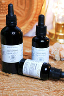 Eine Nahaufnahme von drei schwarzen Tropfflaschen mit Lion's Mane Flüssigextrakt auf einer gewebten Oberfläche, wobei eine Flasche auf der Seite liegt.