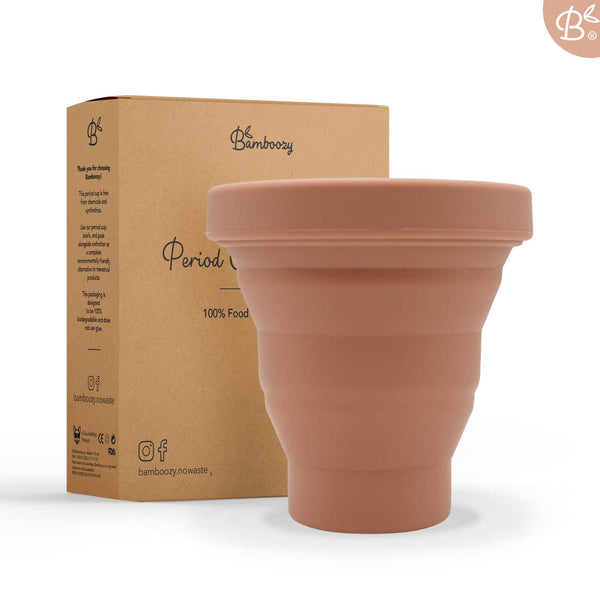 Ein brauner Menstruationsbecher und seine recycelbare Kartonverpackung von Bamboozy, hervorhebend "100% lebensmittelechtes" Material und umweltfreundliche Merkmale.