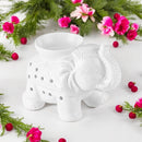 Weiße Elefanten-Duftlampe umgeben von rosa Blüten, roten Beeren und Tannenzweigen.