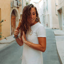 Frau mit lockigem Haar bürstet ihr Haar auf einer Straße in einer europäischen Stadt.