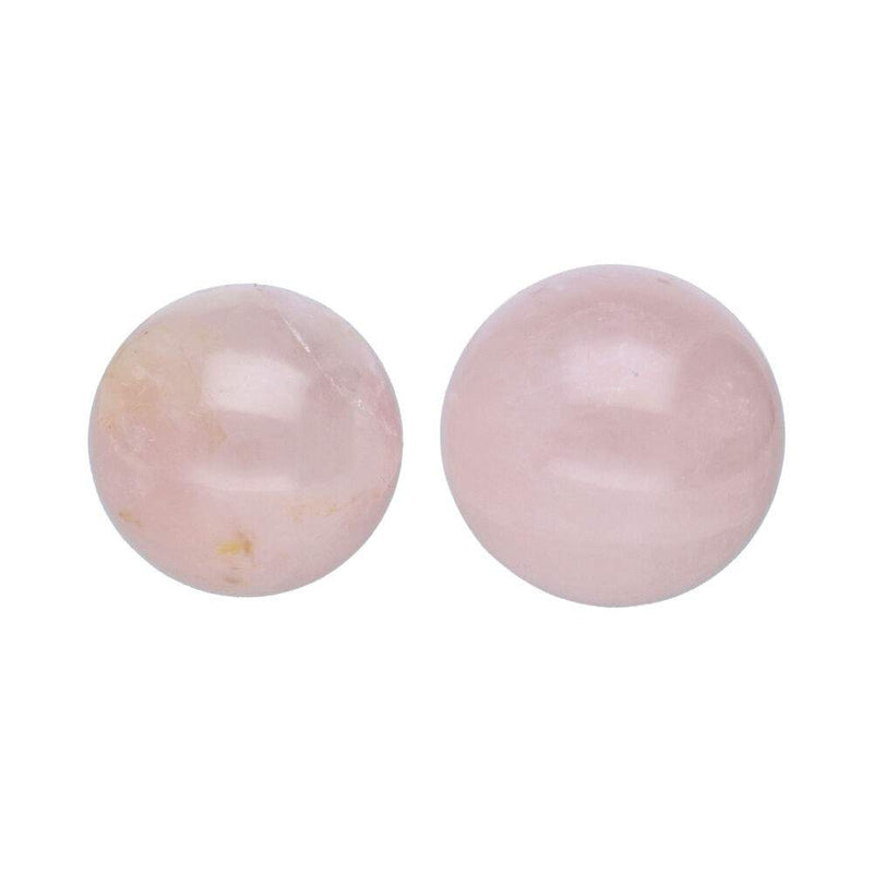 Paar glatter, polierter Kugeln (oder Perlen) aus hellrosa Rosenquarz, die subtile innere Spaltungen zeigen.