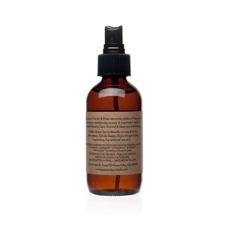 Eine Nahaufnahme des rückseitigen Etiketts der PAAVANI Vata Calming Aromatherapy Spritzer Flasche. Der Text gibt Anweisungen zur Anwendung, empfiehlt Schütteln und Besprühen von Gesicht und Körper, und listet Inhaltsstoffe wie deionisiertes Wasser, Palo Santo, Lavendel, Kardamom und Vetiver ätherische Öle auf.