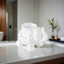 Weiße Elefanten-Duftlampe auf einer hellen Oberfläche in einem Badezimmer.