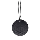 Ein runder, schwarzer Anhänger mit dem eingravierten Muster „Blume des Lebens“, der an einem schwarzen Band hängt. Er hat sichtbare Risse.